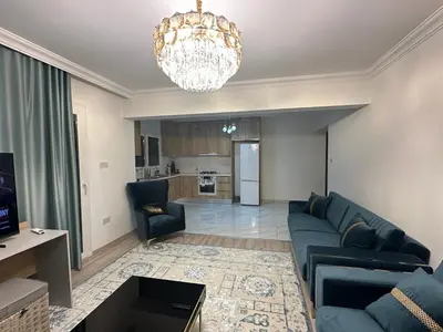 a living room with a blue couch and a chandelier at Park Residence Premium in Larnaka