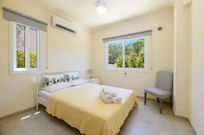 a bedroom with a bed and a chair and two windows at Protaras Holiday Villa - Katia 8B in Protaras