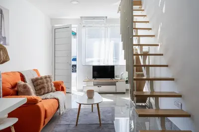 a living room with a orange couch and a staircase at Tangerine Modern 1-BR Apartment in Larnaca in Larnaka