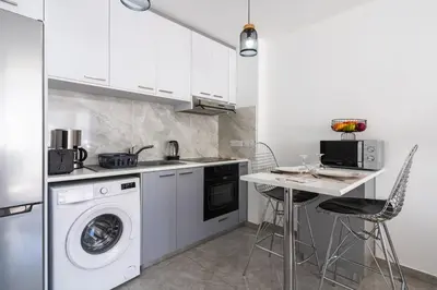 a kitchen with a washing machine and a table at Tangerine Modern 1-BR Apartment in Larnaca in Larnaka
