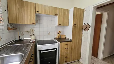 a small kitchen with wooden cabinets and a sink at STAY Sea Gate Apartment in Larnaka