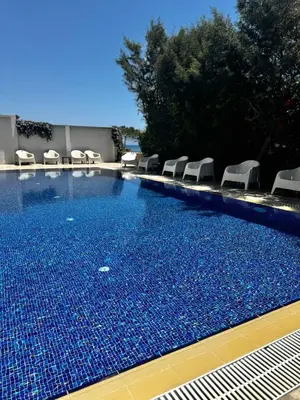 a swimming pool with white chairs and a blue pool at STAY Sea Gate Apartment in Larnaka