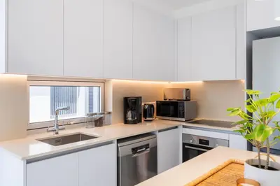 a kitchen with white cabinets and a sink at Aelia - Chic 2-BR Apartment & Balcony in Larnaca in Larnaka