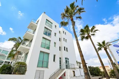 a white building with palm trees in front of it at Crystal Coast in Protaras