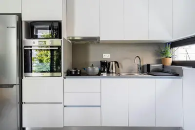 a white kitchen with white cabinets and a sink at Solara - Stylish Balcony Apartments in Larnaca in Larnaka