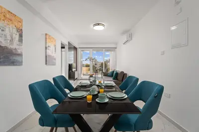 a dining room with a table and blue chairs at Modern 2BR Apartment Near Ayia Napa - Anastasia 101 in Xylophaghou