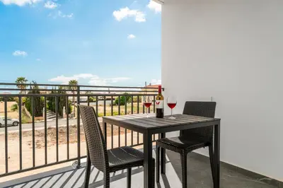 a table with two glasses of wine on a balcony at Modern 2BR Apartment Near Ayia Napa - Anastasia 101 in Xylophaghou