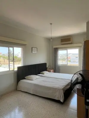 a bedroom with a large bed with two windows at Huge Terrace in peaceful Oroklini in Voroklini