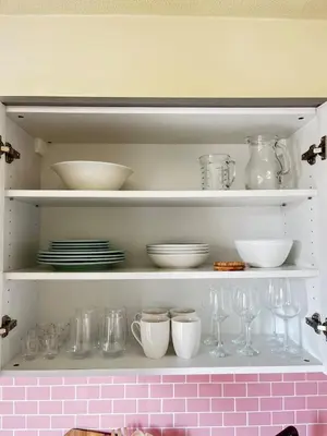 a white shelf with dishes and bowls and glasses at Cozy apartment in Larnaca City Center in Larnaka