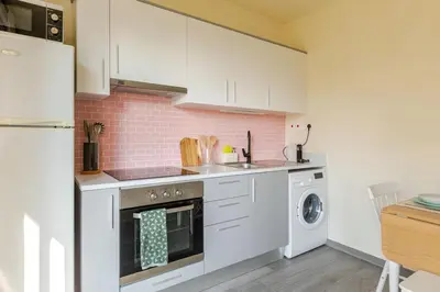 a kitchen with white cabinets and a washer and dryer at Cozy apartment in Larnaca City Center in Larnaka