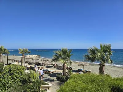a beach with palm trees and chairs and the ocean at Studio by The Sea in Limassol