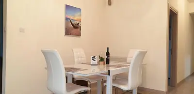 a white dining room table with white chairs and a bottle of wine at Takelena Apartments in Limassol
