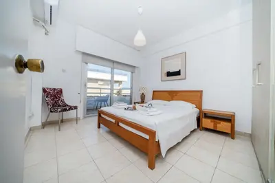 a white bedroom with a bed and a balcony at Seafront central 1 bedroom flat in Limassol