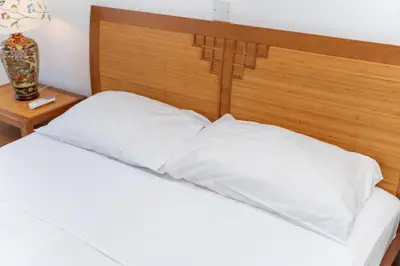 a bed with white pillows and a wooden headboard at Seafront central 1 bedroom flat in Limassol