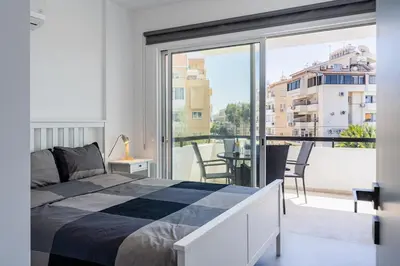 a bedroom with a bed and a large window at Mackenzie Beach Apartment in Larnaka