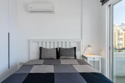 a bedroom with a bed and a large window at Mackenzie Beach Apartment in Larnaka