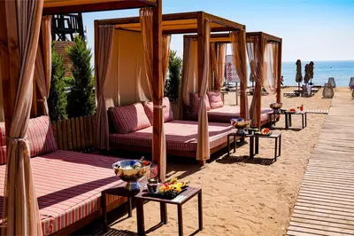 a group of beds on a sandy beach at Mackenzie Beach Apartment in Larnaka