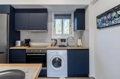 a kitchen with blue cabinets and a washing machine at Mackenzie Beach Apartment in Larnaka