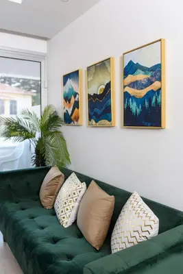 a green couch in a living room with paintings on the wall at Green Island Apartment 102 in Larnaka