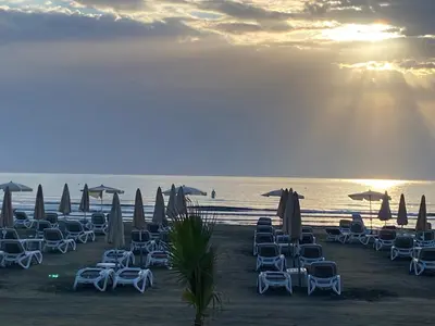a group of chairs and umbrellas on a beach at Mackenzie By the sea one bed Ground floor home in Larnaka