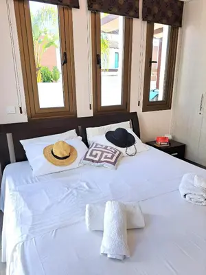 a white bed with a hat and towels on it at Villa Allamare with a pool in Paralimni