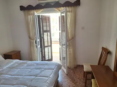 a bedroom with a bed and a table and a window at Big house in center of protaras, near beach in Protaras