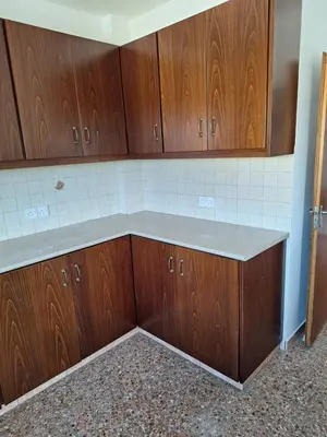 an empty kitchen with wooden cabinets and a counter at Big house in center of protaras, near beach in Protaras