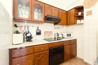 a small kitchen with wooden cabinets and a sink at Spacious Larnaca Beach Apartment in Larnaka