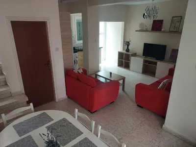 a living room with two red chairs and a table at Sea Breeze Maisonette in Larnaka