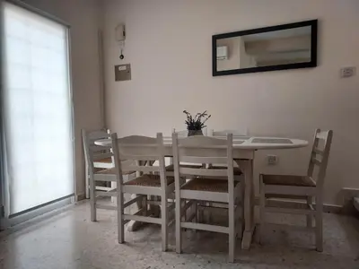 a dining room table with chairs and a mirror at Sea Breeze Maisonette in Larnaka