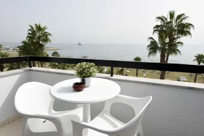 a white table and chairs on a balcony with the ocean at Finikoudes Sunrise Sea View Lux in Larnaka