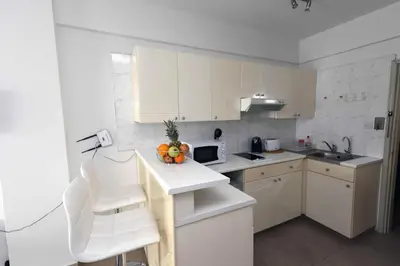 a kitchen with white cabinets and a table and chairs at Finikoudes Sunrise Sea View Lux in Larnaka