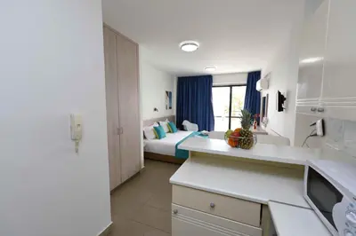 a room with a bedroom with a bed and a kitchen at Finikoudes Sunrise Sea View Lux in Larnaka