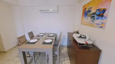 a dining room with a table and chairs and a painting at STAY Suncity Apartment in Larnaka