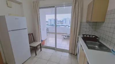 a kitchen with a white refrigerator and a balcony at STAY Suncity Apartment in Larnaka