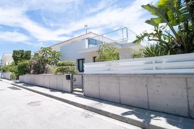 a white house with a fence next to a street at Maestro Villa in Meneou