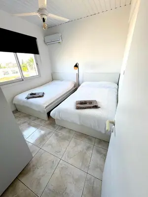two beds in a room with white walls at Casa Sea Breeze in Larnaka