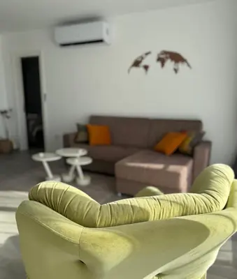 a living room with a couch and a chair at Cozy apartment at Thalassa Beach Resort, Northern Cyprus in Paralimni