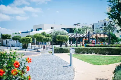 a park with flowers and trees in front of a building at Cozy apartment at Thalassa Beach Resort, Northern Cyprus in Paralimni