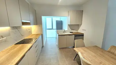 a kitchen with white cabinets and a wooden counter top at Kanika 3 bedroom city beach in Limassol