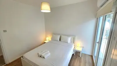 a bedroom with a large white bed with two lamps at Kanika 3 bedroom city beach in Limassol