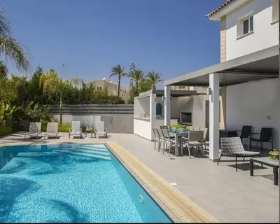 a villa with a swimming pool and a house at Sandy Feet Beach House in Paralimni
