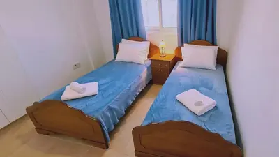 two beds in a small room with blue curtains at STAY Camelia Apartment in Larnaka