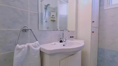 a white bathroom with a sink and a mirror at STAY Camelia Apartment in Larnaka