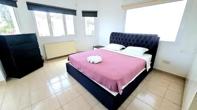 a bedroom with a large bed with a pink blanket at Suburban Family Villa in Limassol