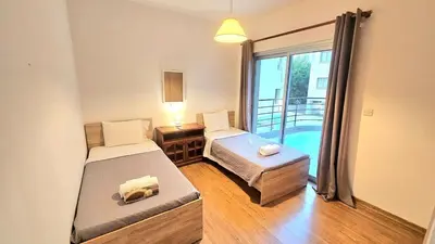 a bedroom with two beds and a balcony at Neapolis city apartment in Limassol