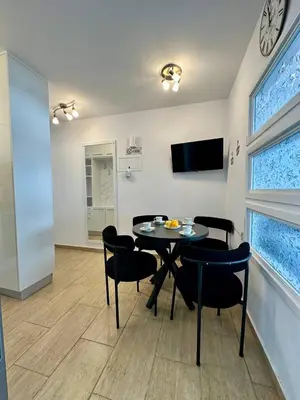 a dining room with a table and chairs and a clock on the wall at Central Napa Escape - Adults Only in Ayia Napa