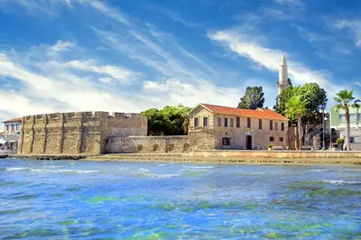 an old building and a church next to the water at Modern Larnaca Beach Apartment in Larnaka