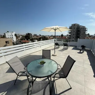 a patio with a table and chairs and an umbrella at Luxurious Penthouse in Larnaca Center 300m From The Beach in Larnaka