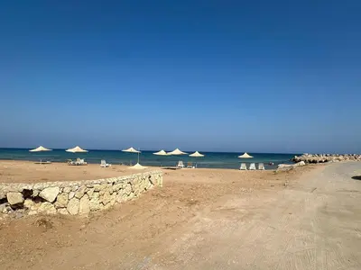 a beach with umbrellas and chairs and the ocean at Garden Cottage Cyprus in Ayia Napa